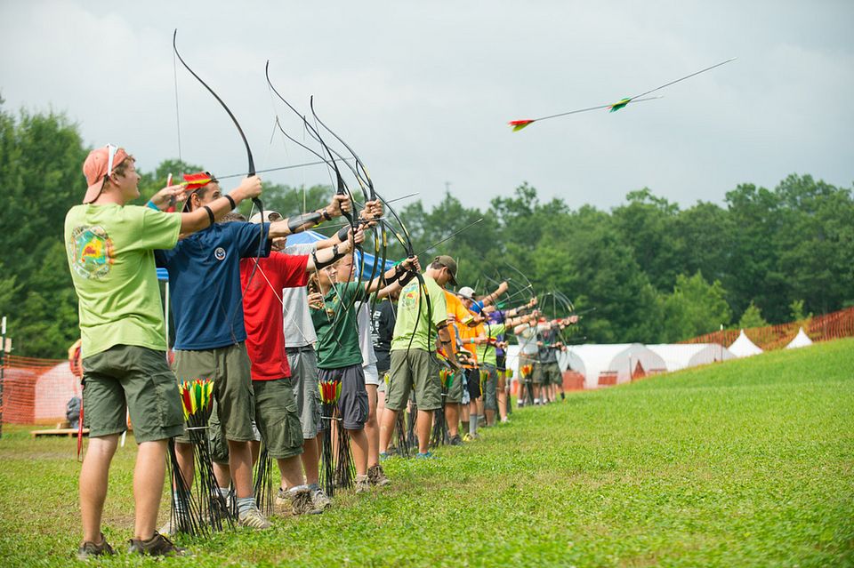 line of scouts shoot bow and arrows on the archery range 