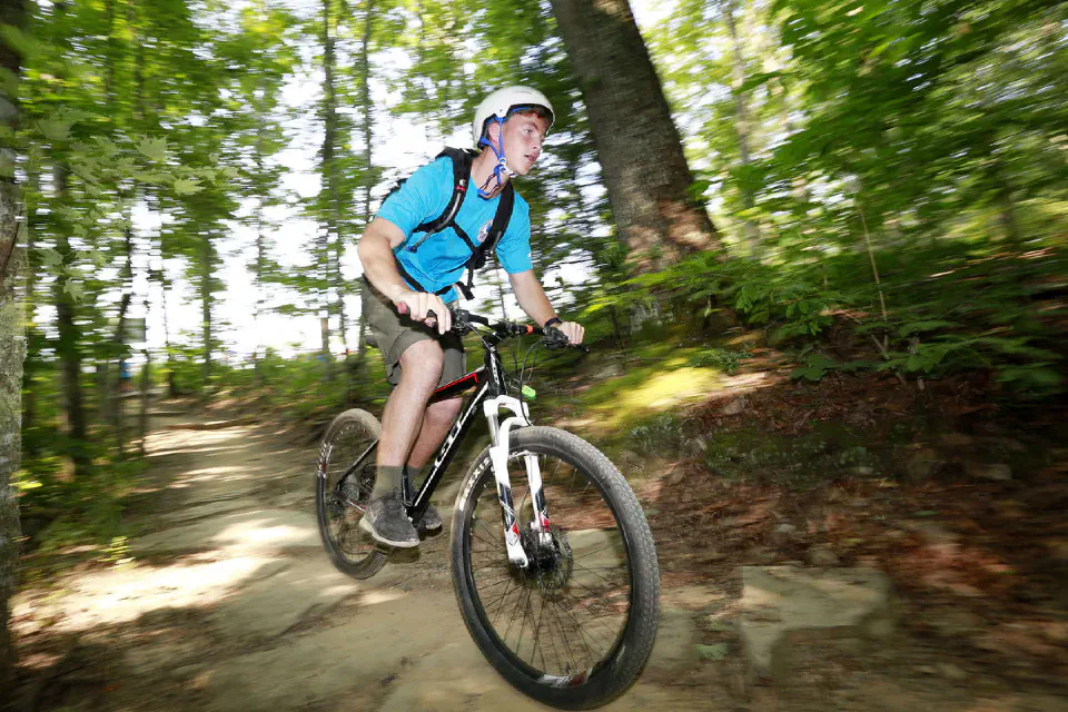 student cycling on a trail in the woods